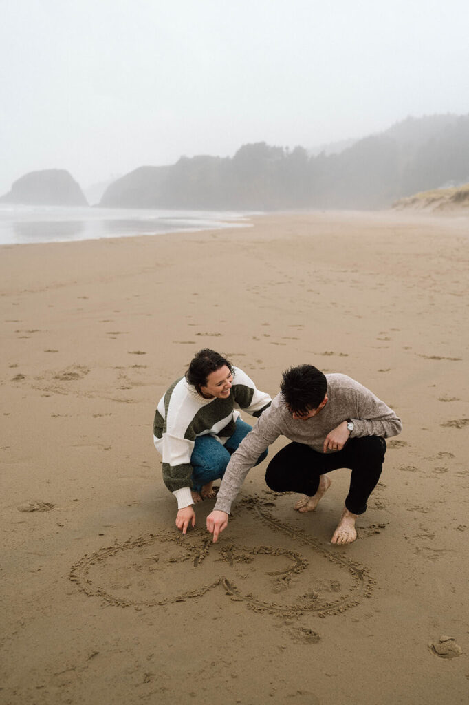 A couple draws their initials in the sand in Oregon. 