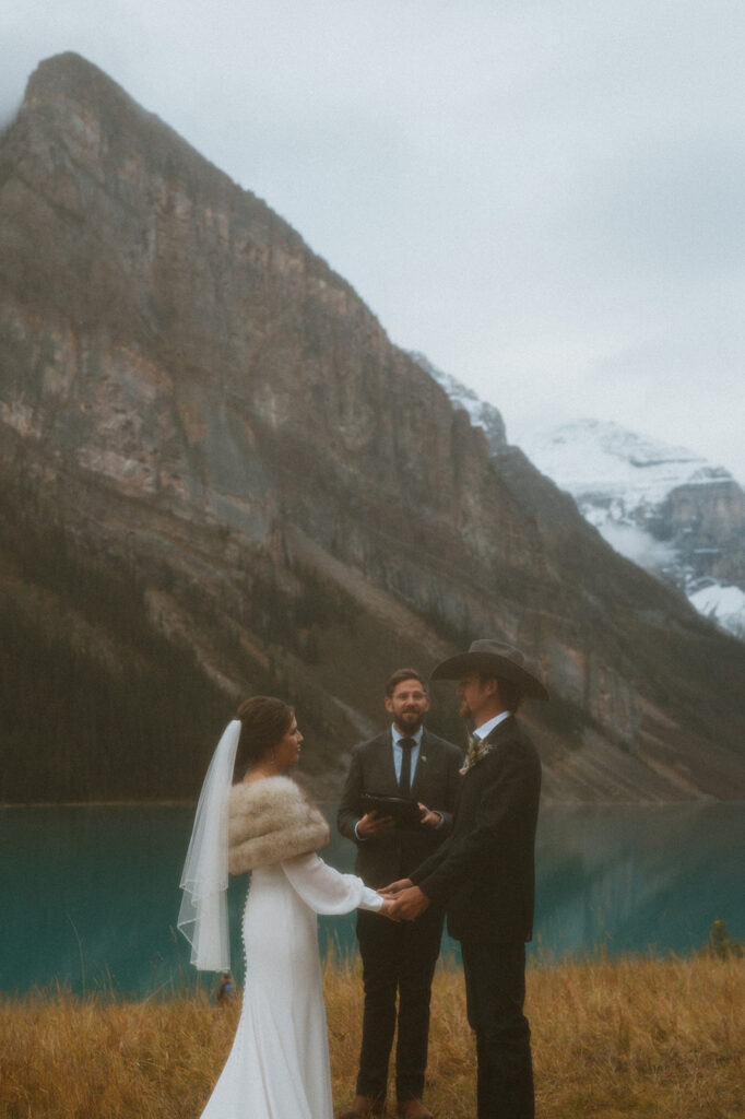 A bride and groom stand holding hands during their vow ceremony officiated by Cole from Married By Cole in Banff.