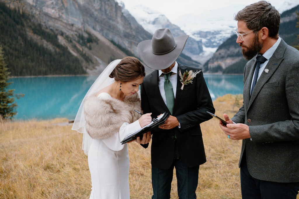 A couple signs their marriage certificate with their officiant Married By Cole during their National Park elopement in Banff.