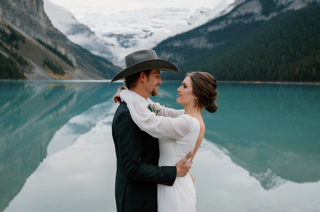 A couple embraces near the shores of Lake Louise during their intimate Banff elopement in Alberta, Canada. 