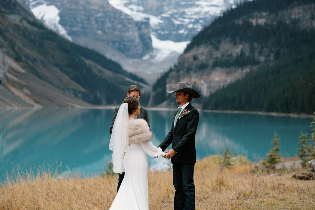 A couple holds hands with one another during their Lake Louise elopement as they say intimate vows.