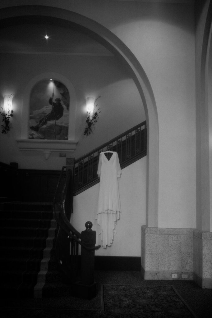 A long sleeve white wedding dress is seen on a hanger on a staircase at Fairmont Chateau Lake Louise.