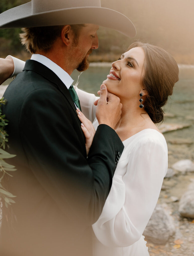A groom holds his bride's chin while he goes in for a kiss during their intimate Banff elopement. 