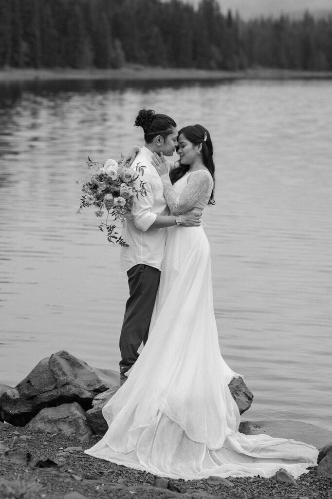 A couple embraces for wedding portraits near a lake.