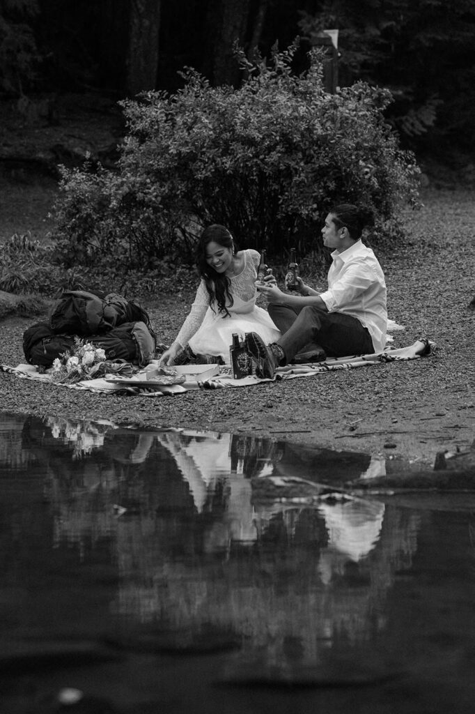 An elopement couple shares a romantic lakeside picnic.