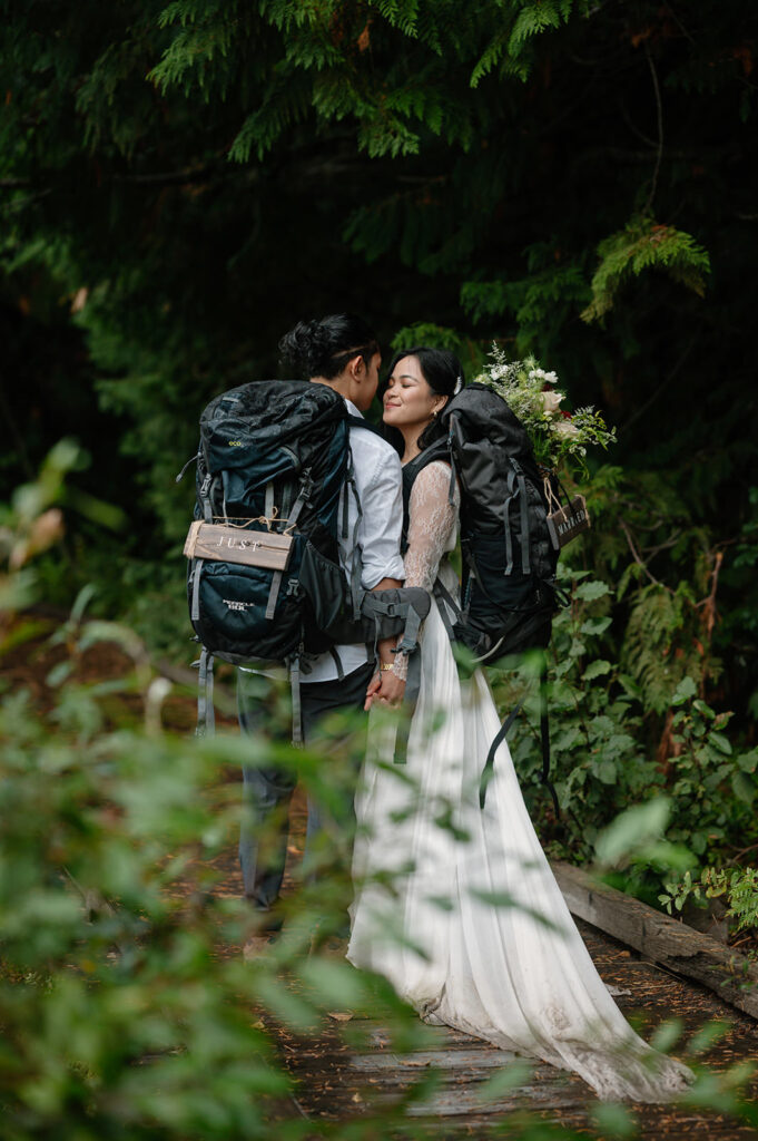 A couple embraces while wearing elopement hiking packs.