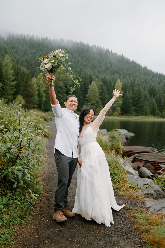 A couple cheers in excitement to their intimate wedding on Trillium Lake.