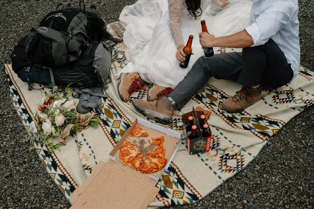 A picnic blanket with pizza and beer.