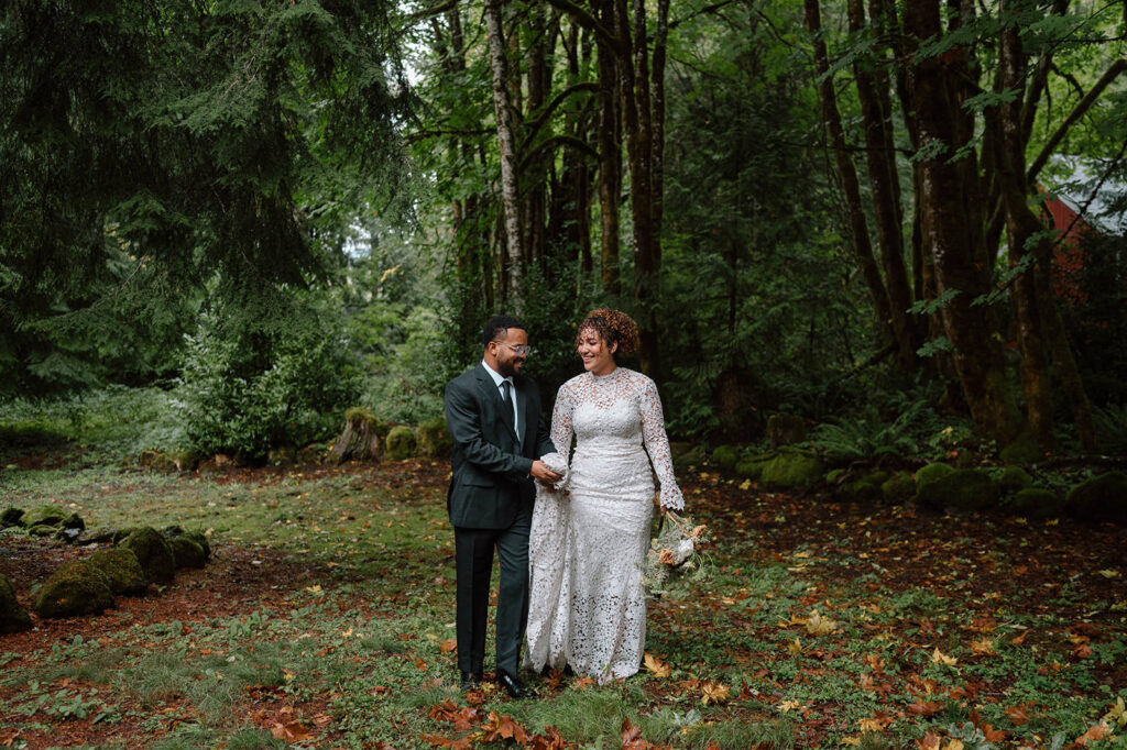A couple walks hand in hand through a forest in Oregon during their wedding.