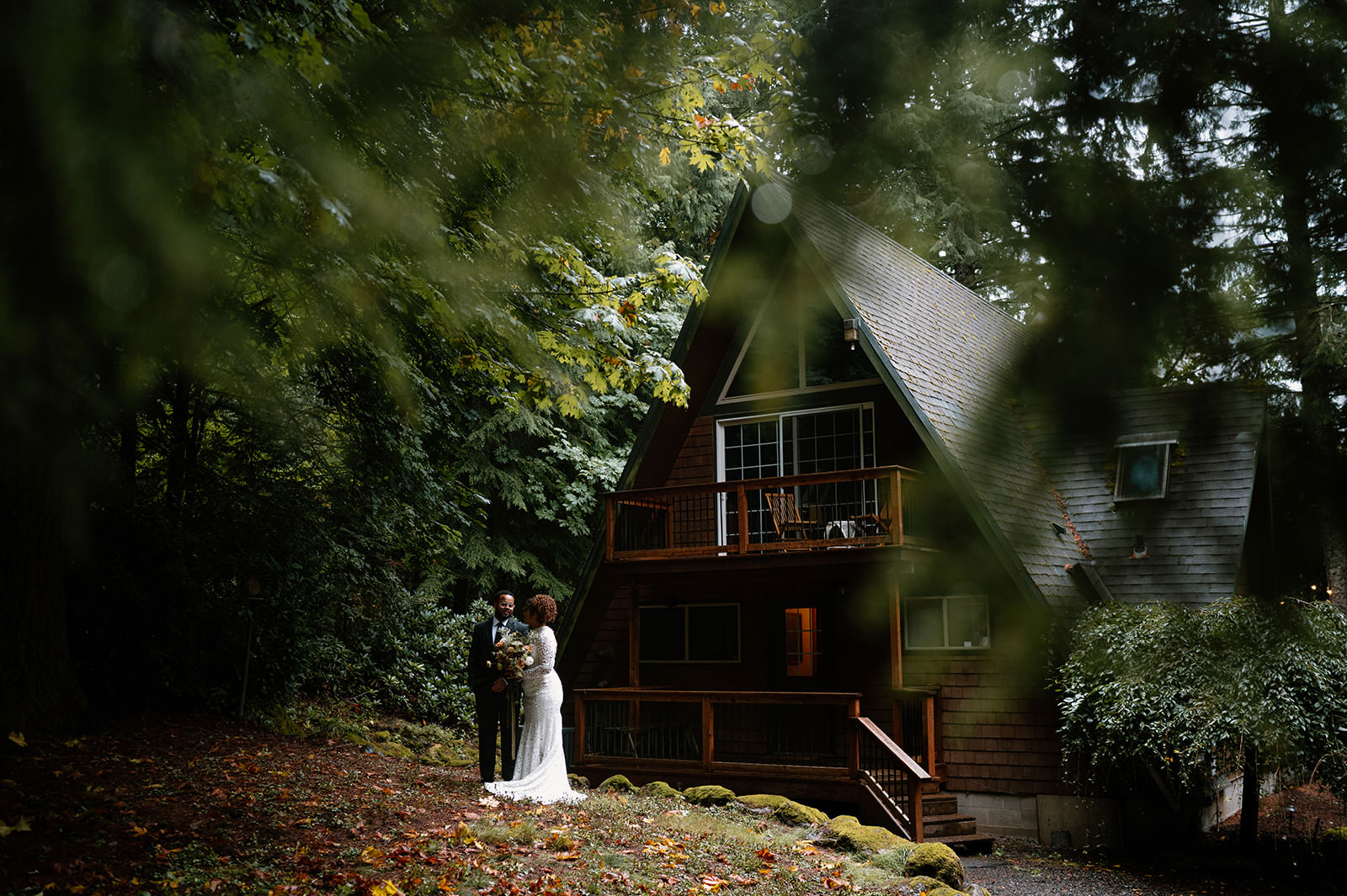 A couple is seen through evergreen trees at an Oregon Airbnb elopement.