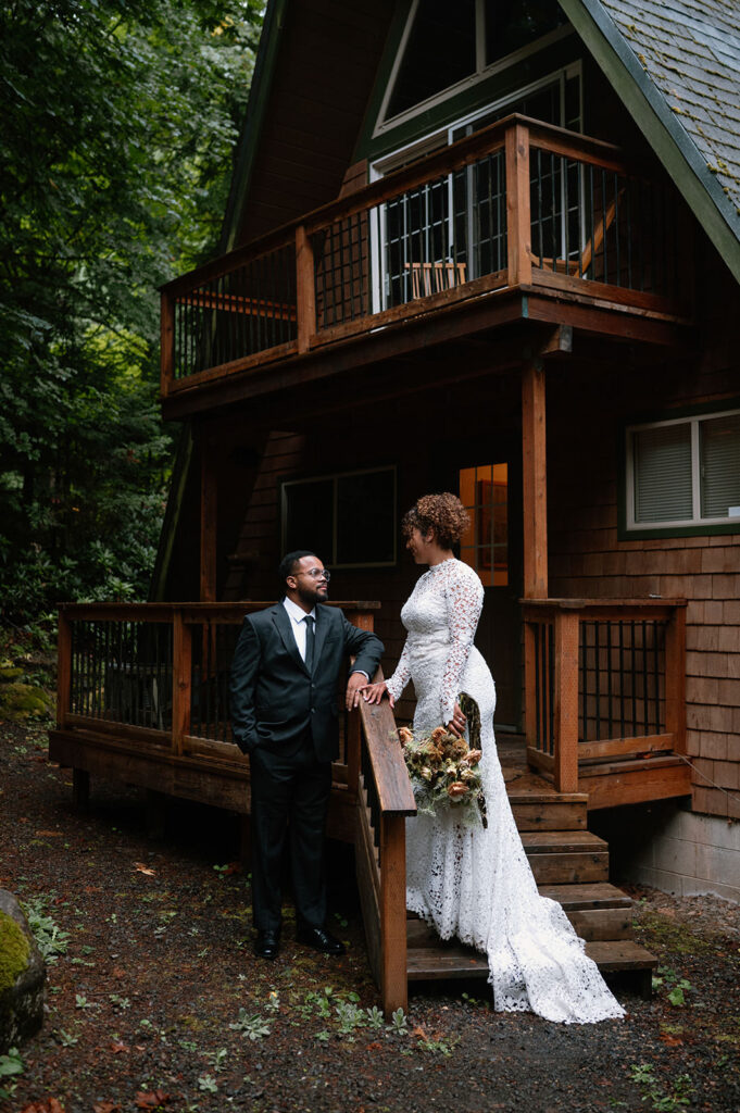 A couple admires one another while standing on a cabin staircase.