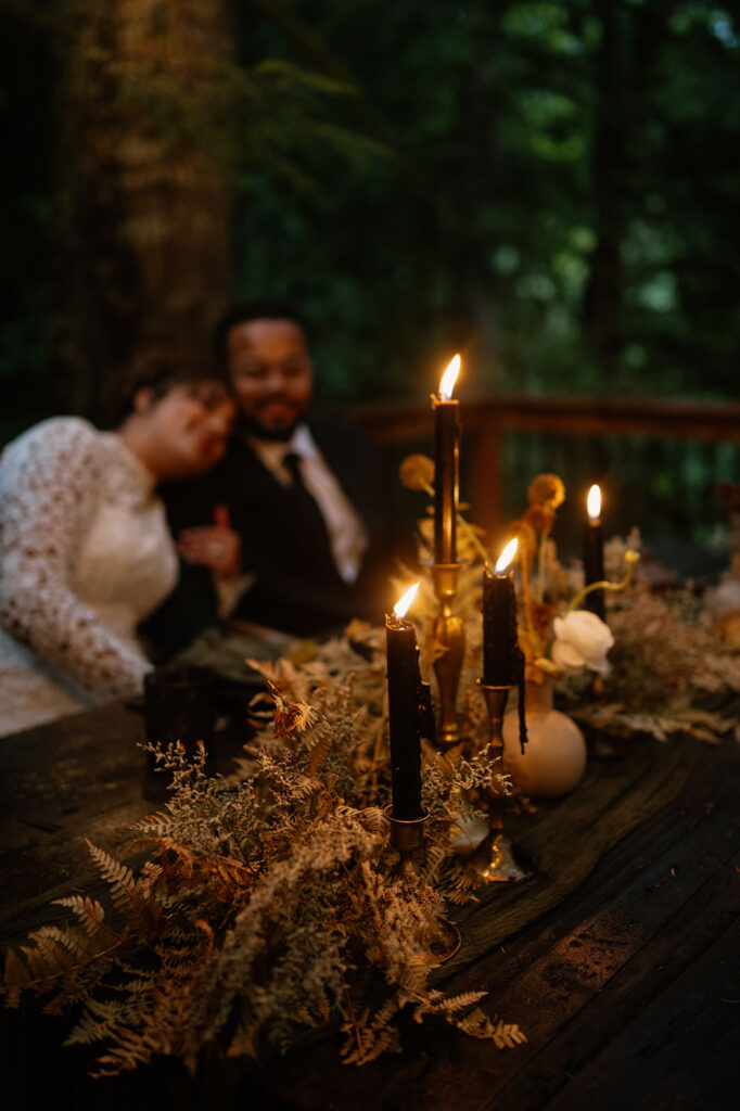 A dark, floral tablescape with candles.