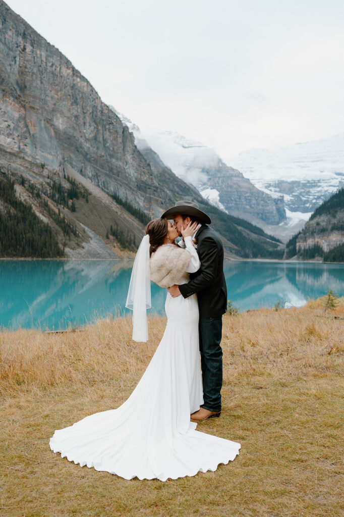 A bride and groom elope in Banff and share a kiss near Lake Louise. 