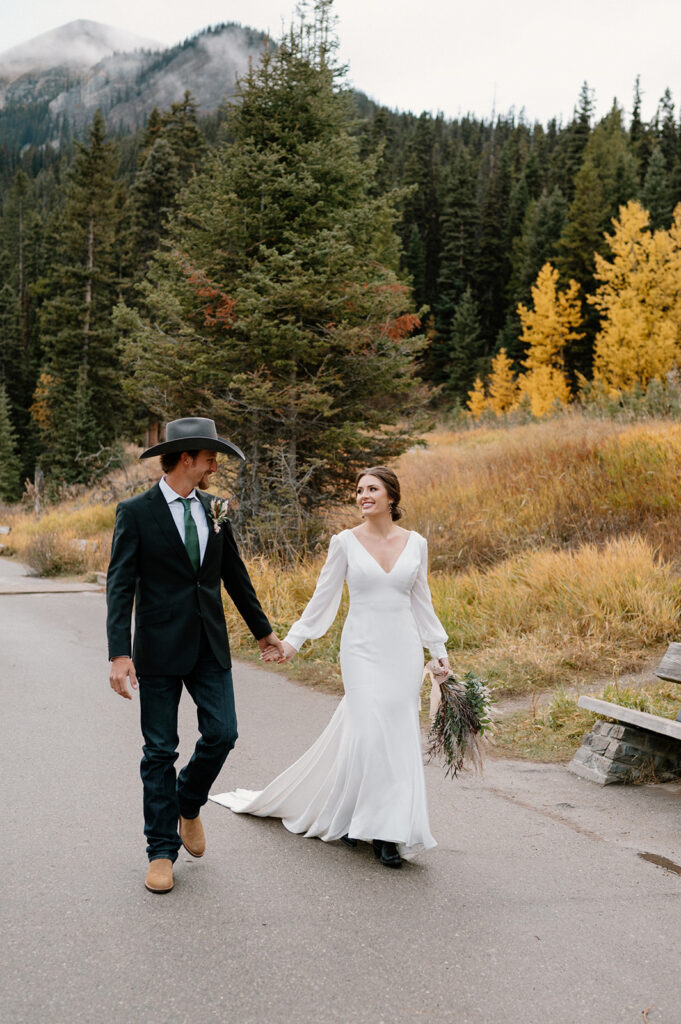 A couple strolls along a paved path at Lake Louise during Autumn in Banff. 