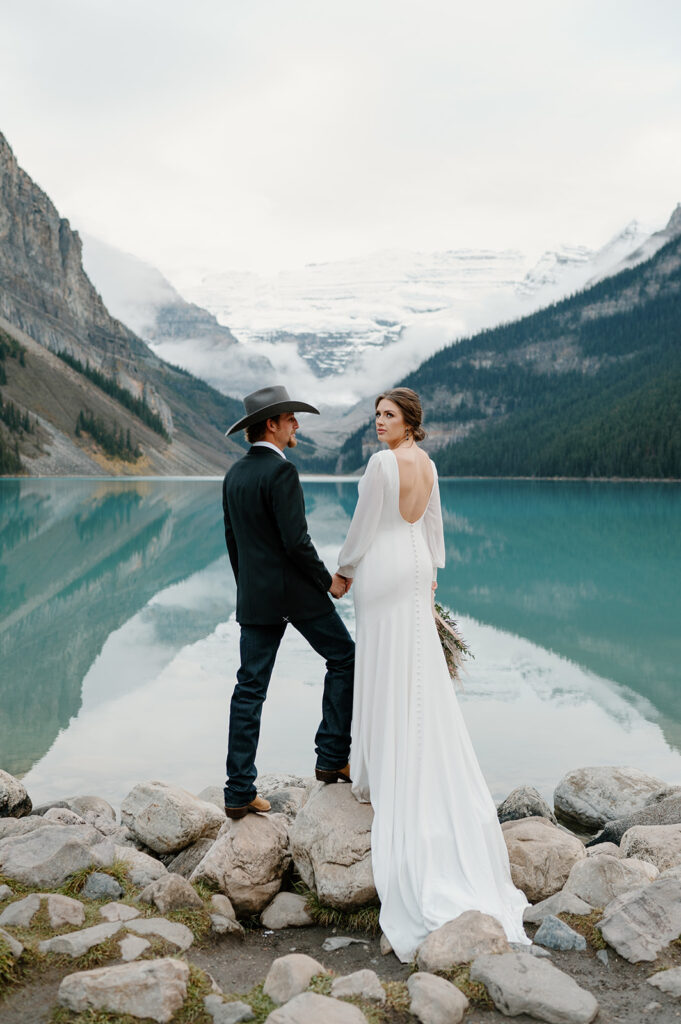 A bride and groom take lakeside wedding portraits at an alpine lake in Banff.