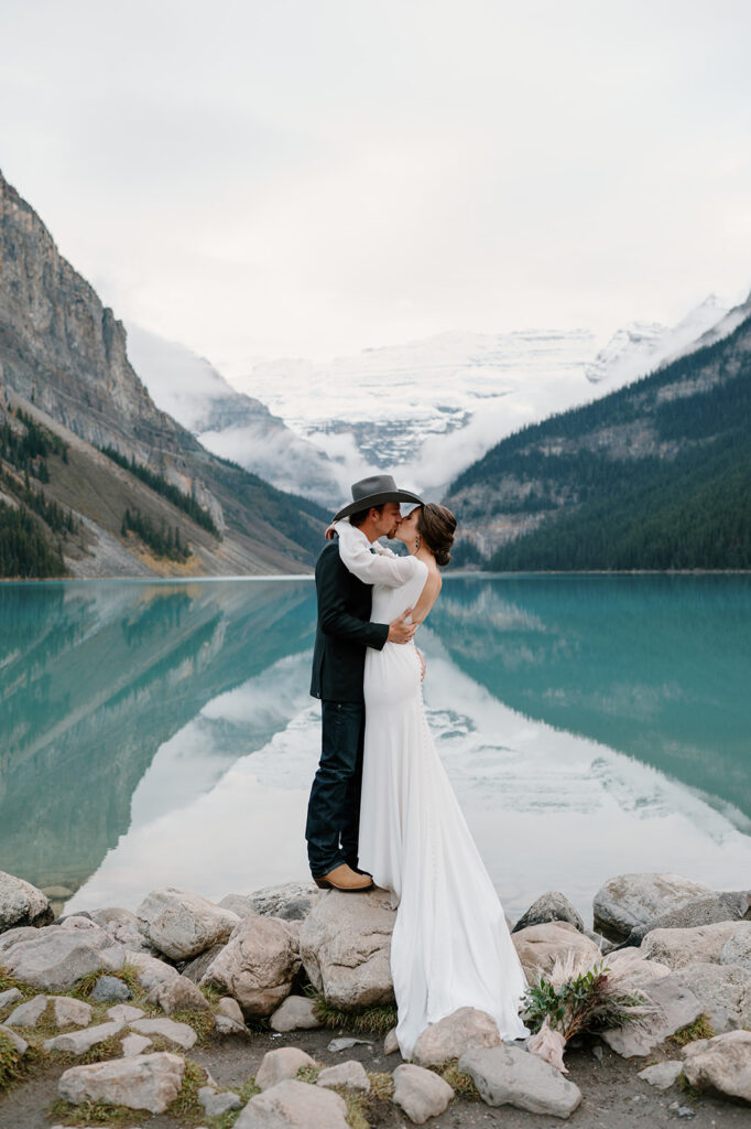 A bride and groom stand in front of Lake Louise during their Fall Banff elopement.