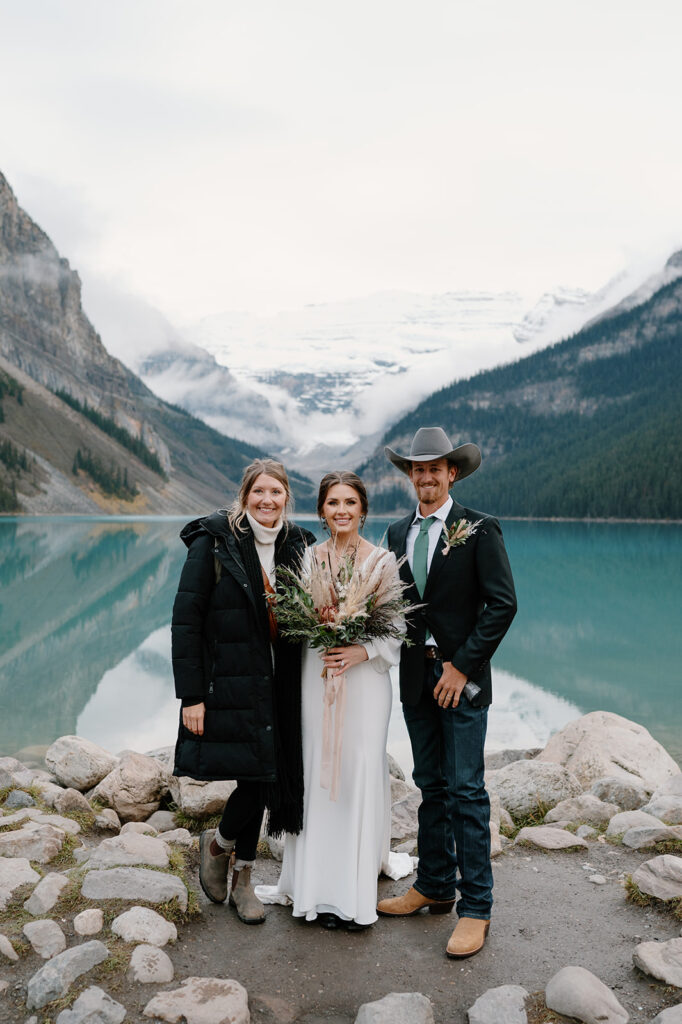 Reagan from Regan Taylor Photography stands next to a Banff elopement couple at Lake Louise in Alberta. 