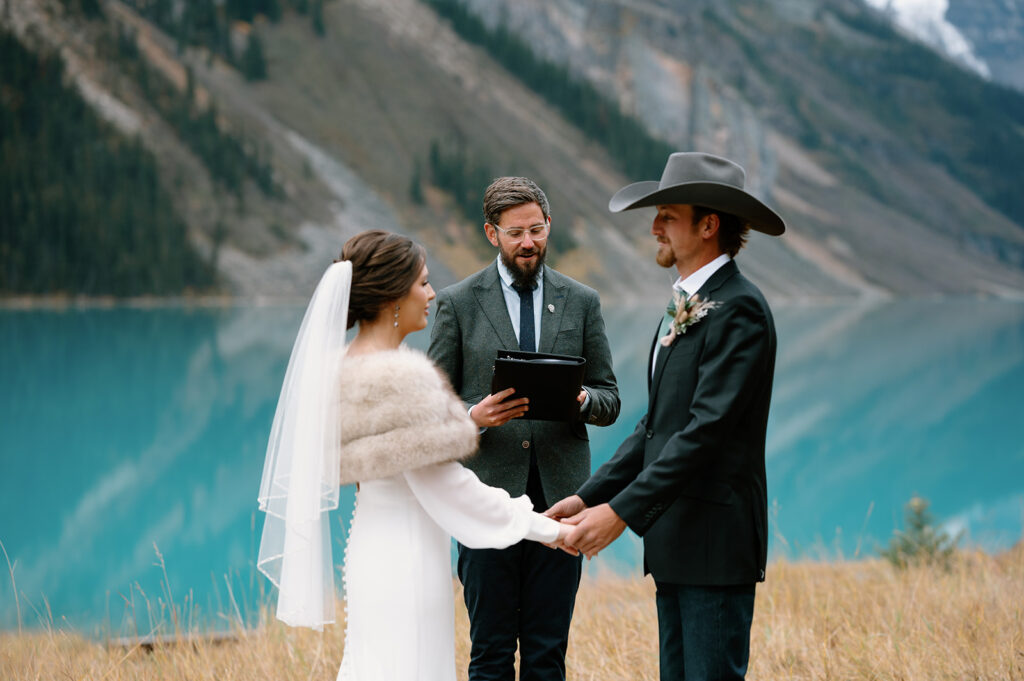 A bride and groom hold hands with one another while their officiant, Cole from Married By Cole, asks them to recite their vows. 