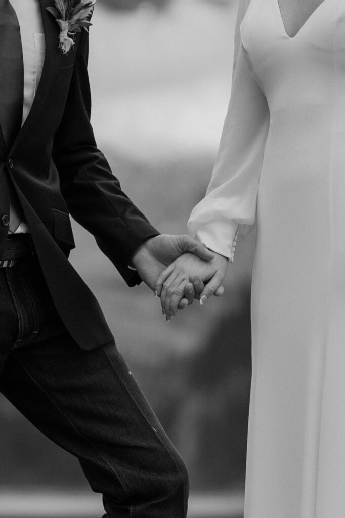 A couple holds hands during their intimate Banff elopement at Lake Louise in Alberta, Canada. 