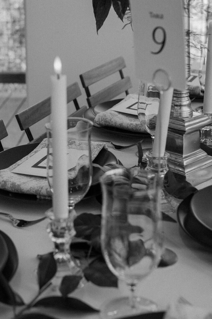 A detail shot of a microwedding tablescape with taper candles, glassware and printed cloth napkins. 