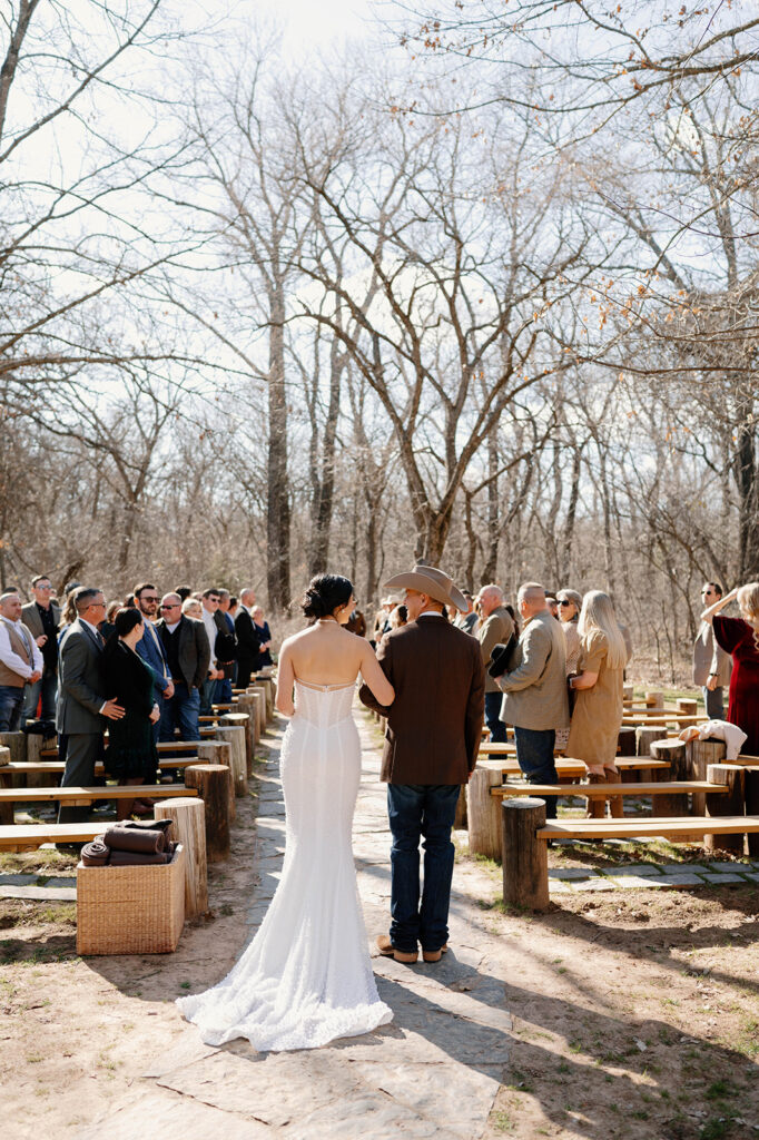 The father of the bride walks his daughter down the aisle at an outdoor microwedding. 