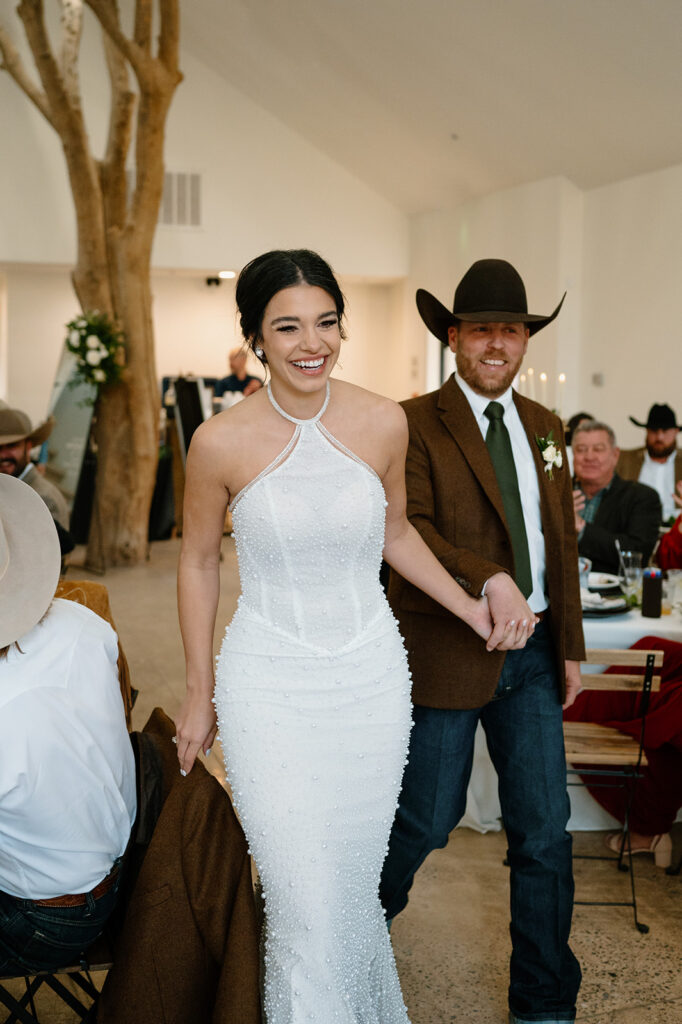 A bride and groom make their grand entrance into a small reception space during their microwedding. 