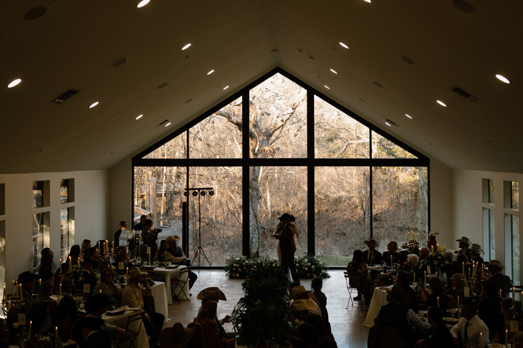 A bride and groom share a first dance in an intimate reception space with a large a-frame window. 