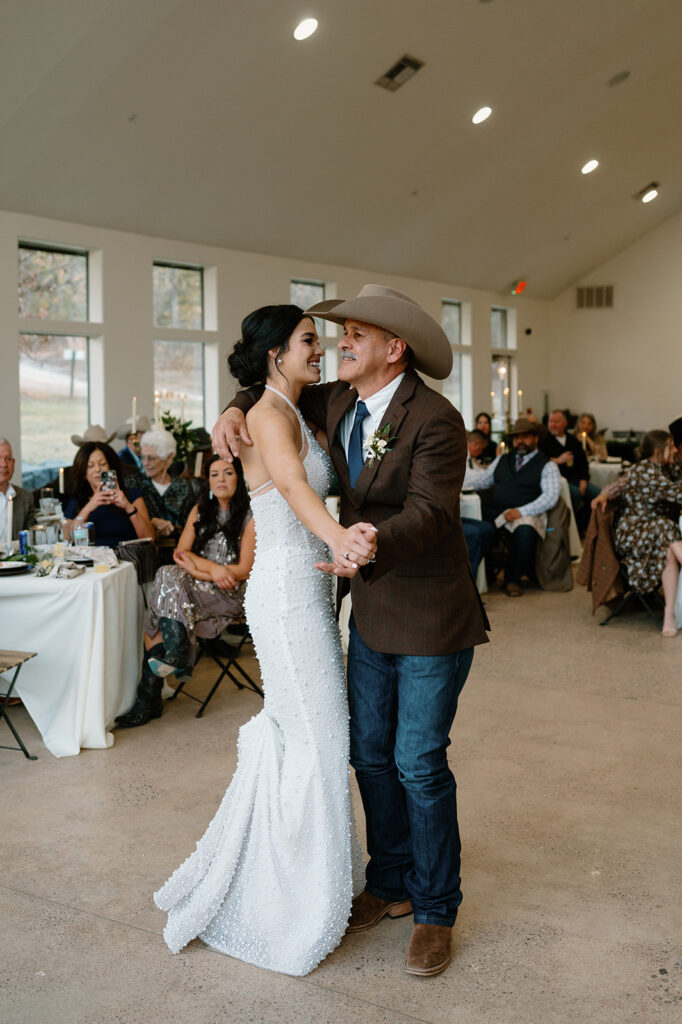 A bride dances with her dad during a father-daughter dance during an indoor microwedding reception. 