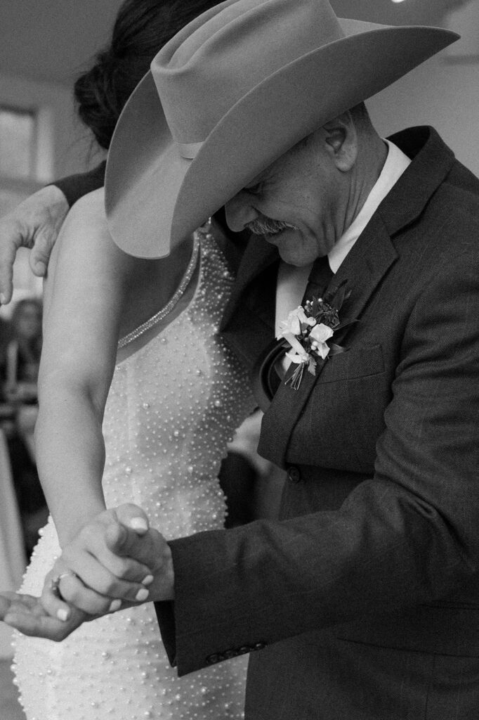 A bride and her dad share a father-daughter dance during a rustic microwedding reception. 