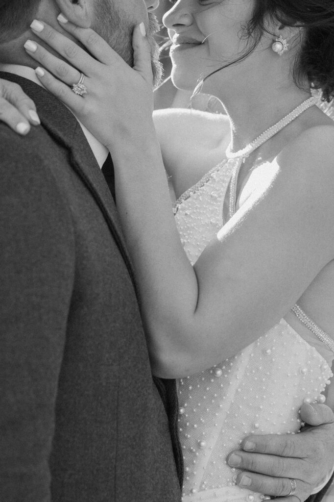 A groom holds his bride close during outdoor wedding portraits. 