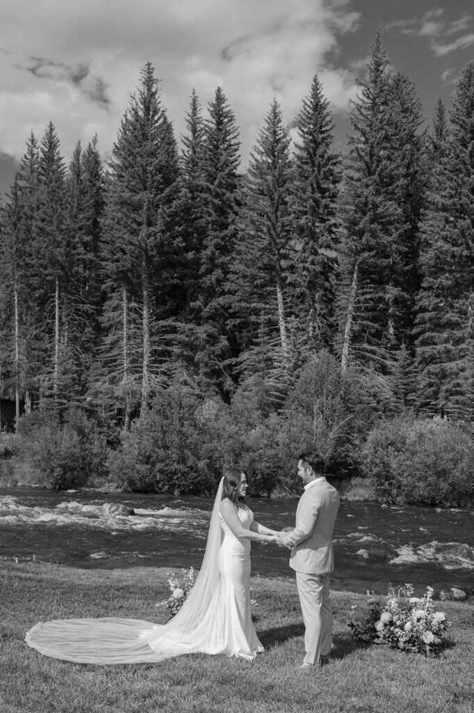 A bride and groom share wedding vows near a river in Crested Butte at Harmels On The Taylor. 