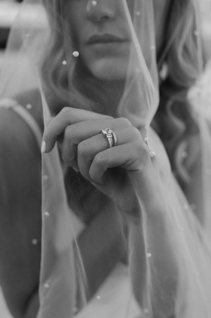 A bride's face is covered by a tulle wedding veil with embellishments.