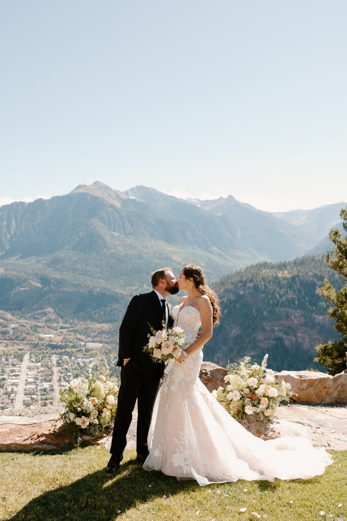 A couple shares a kiss during their wedding portraits overlooking Ouray at Gold Mountain Ranch.