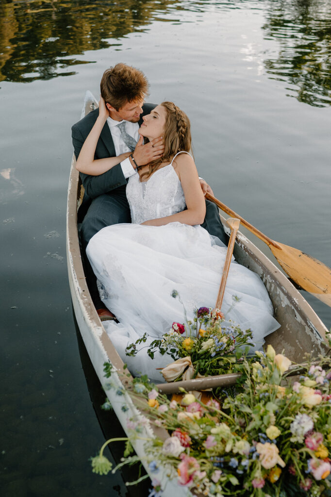 A couple goes in for a kiss on a pond in a row boat at Shaw's River Ranch during their Colorado wedding ceremony. 