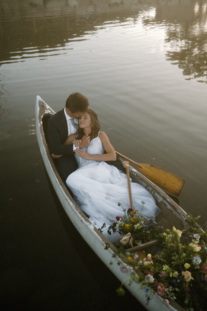 A bride lays on her grooms chest while sitting in a row boat on a pond at Shaw's River Ranch. 