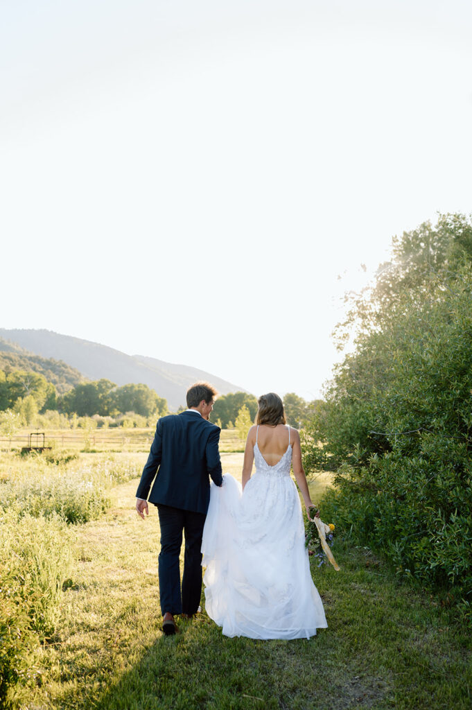 A couple walks through a ranch meadow during their intimate wedding on Shaw's River Ranch. 