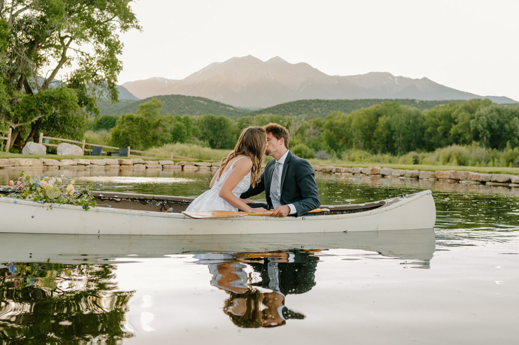 An elopement couple kisses in a row boat on a pond at Shaw's River Ranch in Salida, Colorado. 