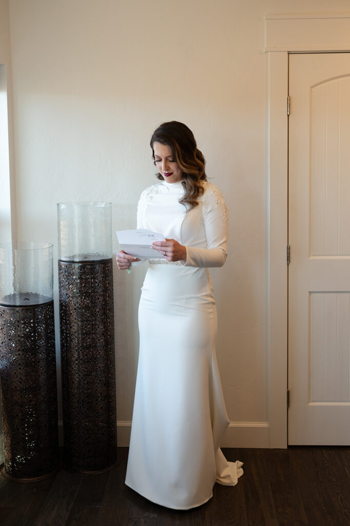 A bride in a long, white wedding gown reads a letter addressed to her before her Utah elopement at a Moab Airbnb. 