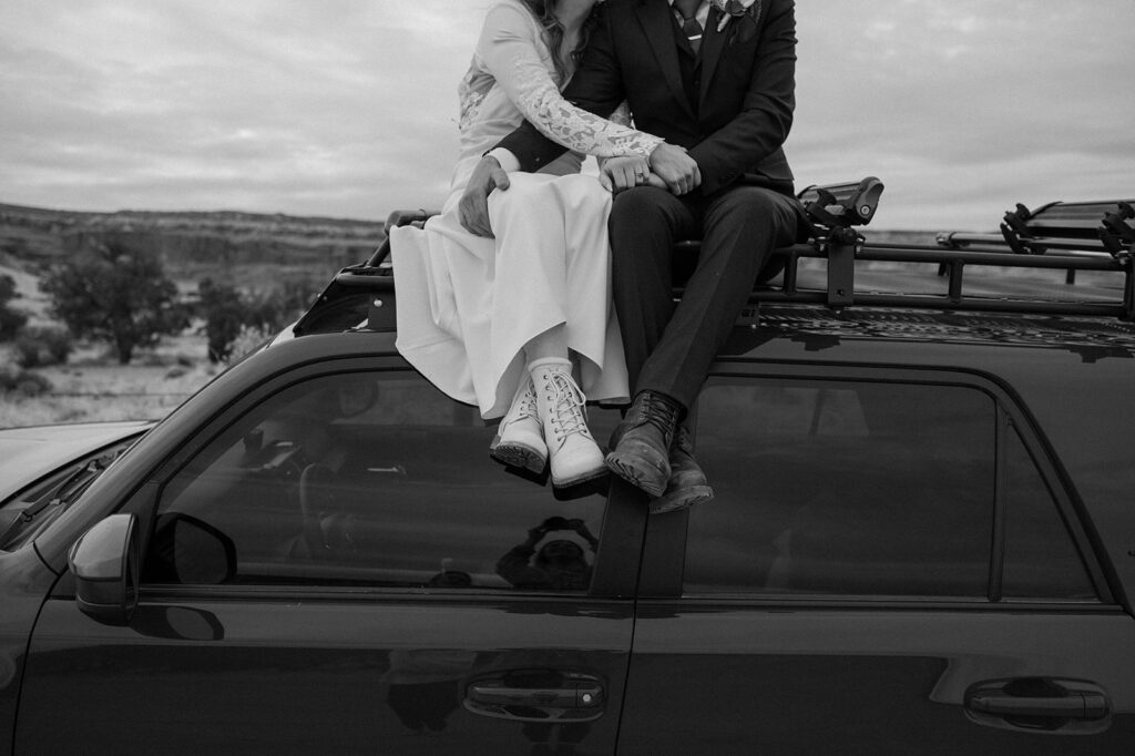 A couple sits on the roof of an off-roading vehicle during their Moab elopement in the desert. 