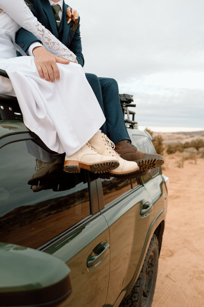 A Moab elopement coupl's boots are seen as they sit atop a dark green 4x4 vehicle during their desert elopement. 