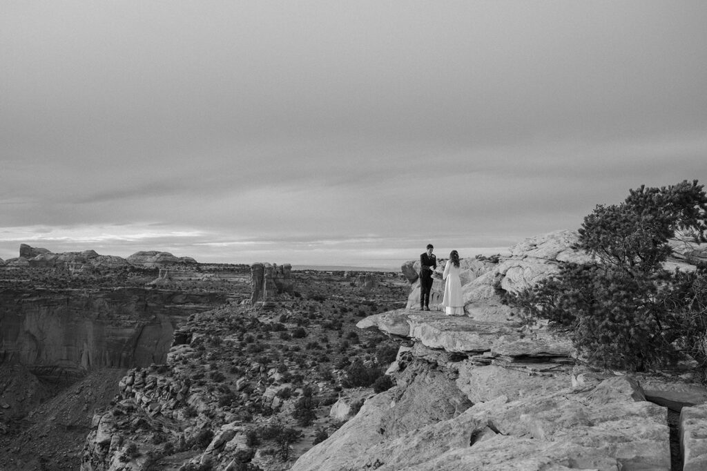 An elopement couple exchanges vows with standing on a red rock overlook in Canyonlands National Park. 