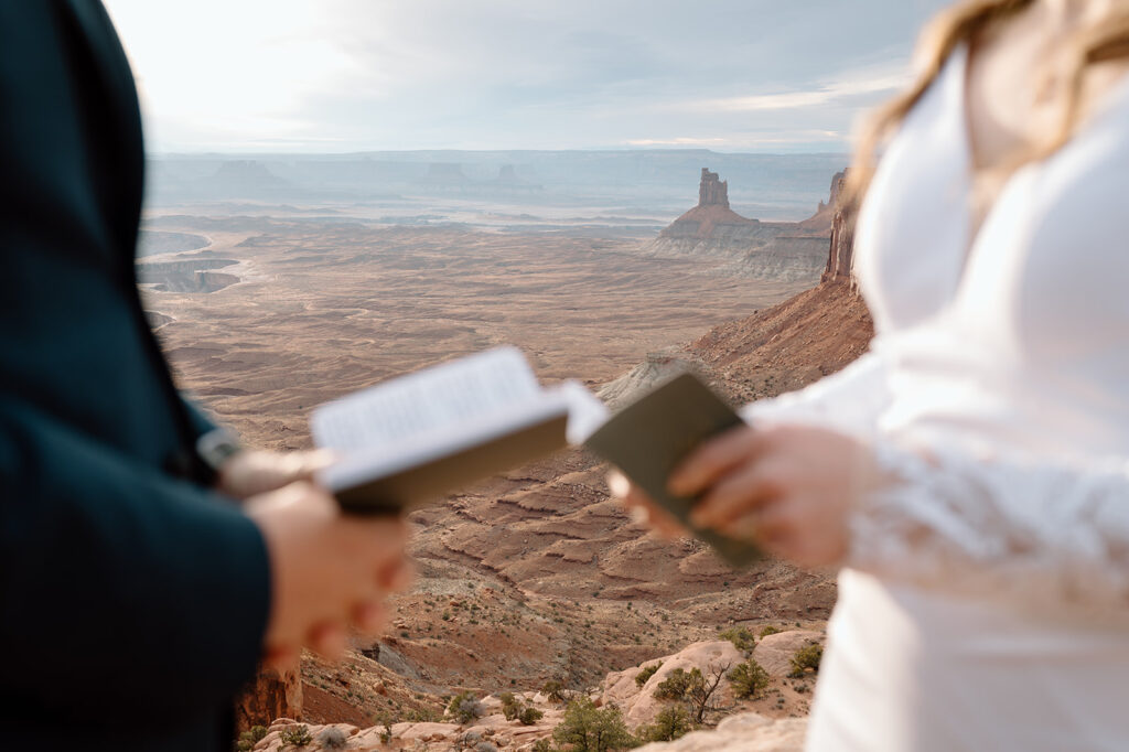 A couple holds green vow books during their Canyonlands National Park elopement ceremony in Moab.  