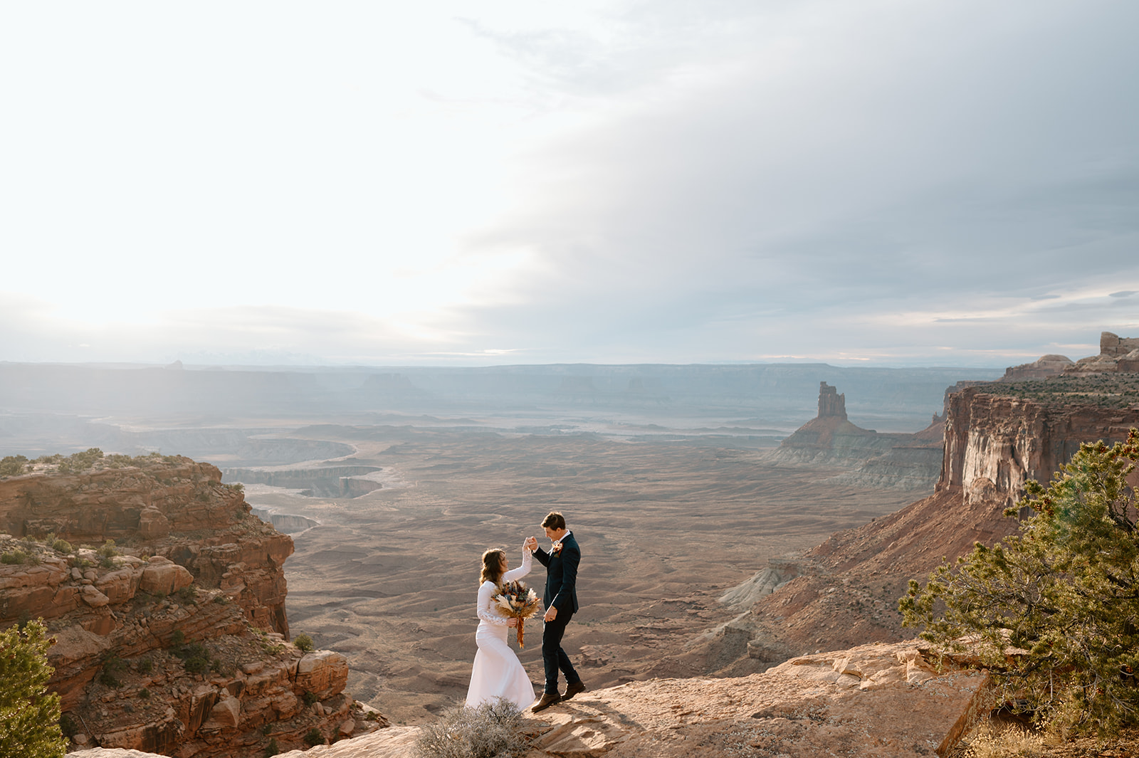 A Moab elopement couple stands on an overlook in Canyonlands National Park at Sunset.