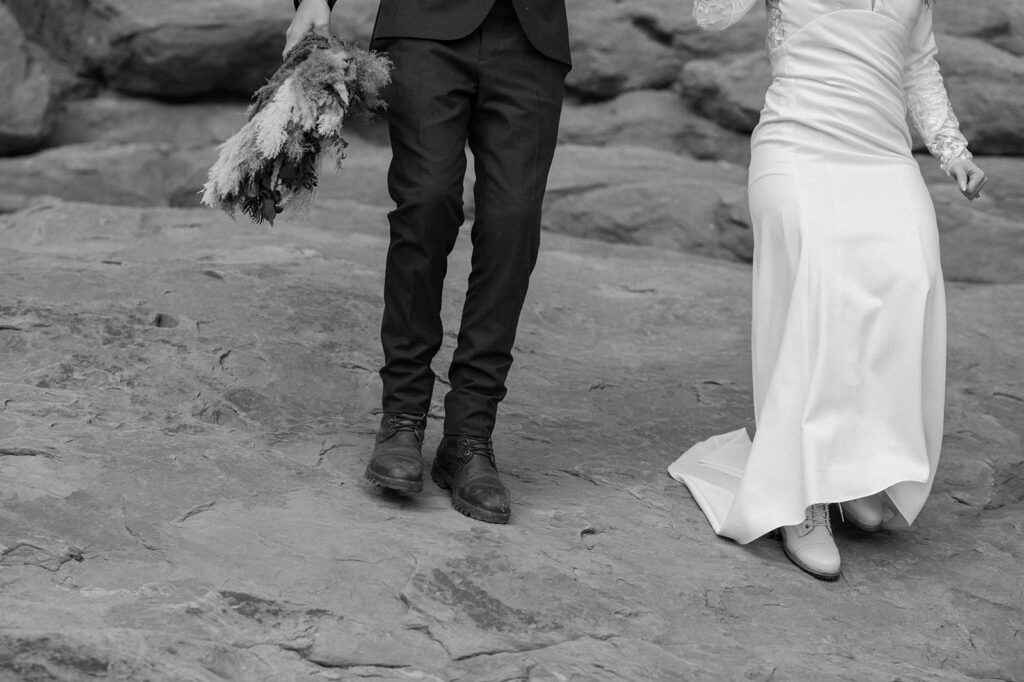 A couple walks atop red rocks in Moab during their Utah elopement in Arches National Park. 