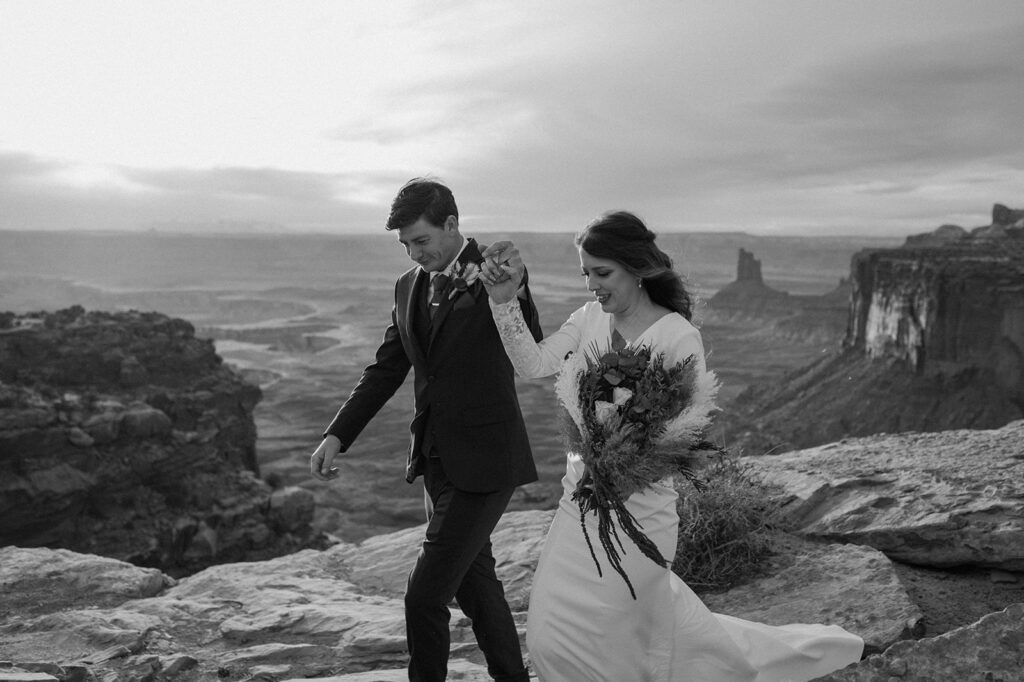 A groom guides his bride as they walk along an overlook in Canyonlands National Park. 