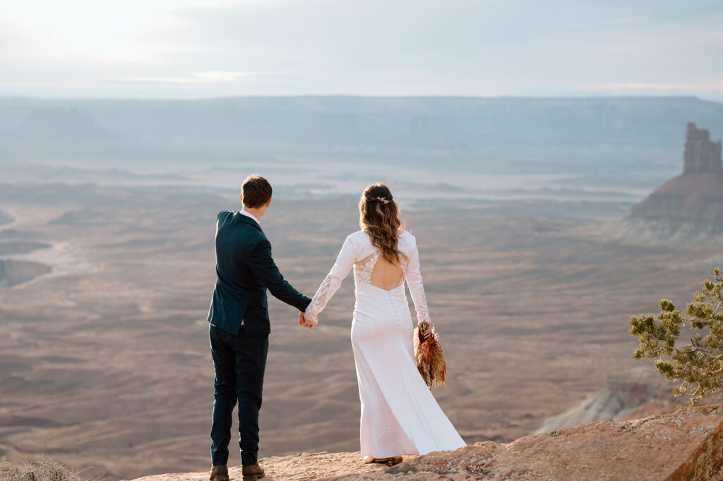 A couple admires Canyonlands National Park during their Sunset desert elopement in Moab, Utah. 