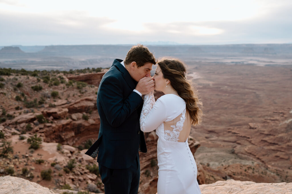 A couple warms one another hands on an overlook in Canyonlands National Park during their Moab elopement. 