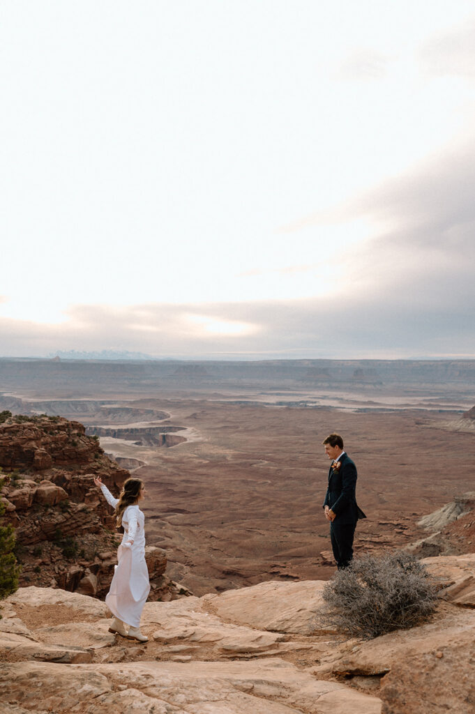 A bride dances while her groom watches in admiration on an overlook in Canyonlands National Park. 