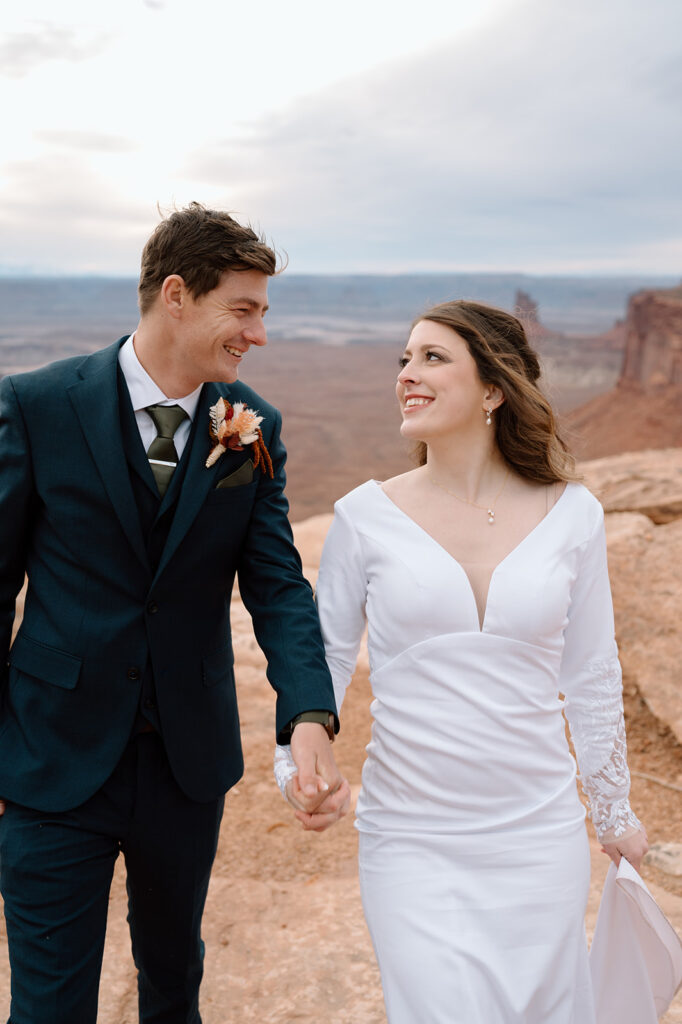 A Utah elopement couple smiles at one another and holds hands during their Canyonlands National Park ceremony. 