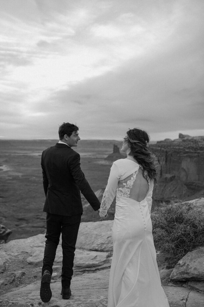 A couple walks along Grand View Point Overlook in Canyonlands National Parking during their Sunset desert elopement in Utah. 